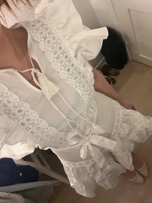 Vit kortklänning med spets och volang - Supersöt vit kort klänning från Sellpy. perfekt nu till studentennn.