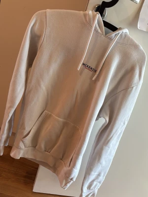 Vit McKenzie hoodie - Hej! Säljer en stilren vit hoodie från McKenzie i storlek M. Klassisk modell med huva, snörning och magficka framtill. Diskret logga på bröstet. Tröjan är i fint skick, sparsamt använd och utan större slitage. Perfekt som vardagsplagg – både bekväm och lätt att matcha med olika outfits. Säljes då den inte längre passar min son. Kontakta vid funderingar!🙂