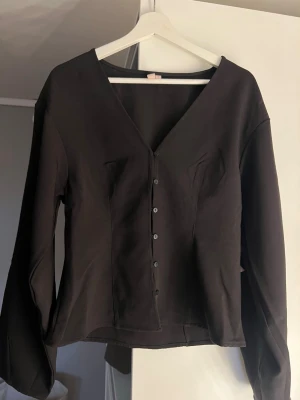 Svart v-ringad blus med knappar - Superfin svart blus med v-ringning och knäppning framtill från Nelly! Aldrig använd, pris kan diskuteras ❣️