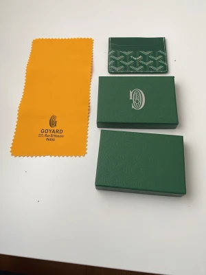 Grön plånbok - Snygg grön plånbok med det klassiska vita mönstret och loggan framtill. Tillverkad i exklusivt läder och levereras med original ask och gul putsduk. Perfekt för kort och ID, smidig att ha i fickan.