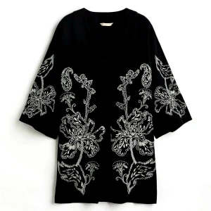 Svart kortklänning med broderade blommor - Svart kortklänning med v-ringning och vida trekvartsärmar frå än H&M. Klänningen har stora, ljusa blombroderier framtill och på ärmarna som ger en unik och cool look. Perfekt för dig som gillar statement-plagg med snygga detaljer.