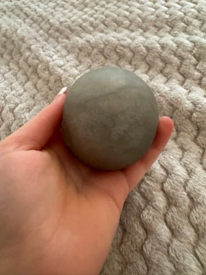 Silvrig Stressboll - Säljer en rund, slät grå sten som ligger skönt i handen. Perfekt som dekoration, pappersvikt eller för dig som gillar att samla på fina stenar. Stenen har en naturlig matt yta och en jämn form.