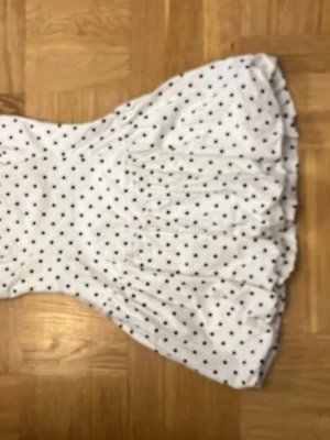 Vit prickig kortklänning - Söt vit kortklänning med svarta prickar och puffig kjol. Klänningen var spagetti ärmar. 