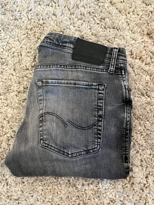 jack & jones jeans slim/glenn  i storlek 32/32. säljer mina gammla favorit jeans i bra skick - Snygga grå slim fit jeans från jack & jones med klassisk femficksmodell och diskret slitning på låren. Jeansen har en svart patch bak i midjan och är tillverkade i mjuk denim med stretch för extra komfort.