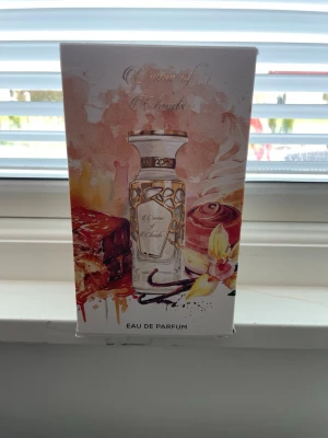 Crème of Clouds Eau de Parfum - Crème of Clouds Eau de Parfum från Fragrance World kommer i en lyxig vit och guld kartong med illustrationer av choklad, vanilj och blommor. Flaskan har eleganta gulddetaljer och rymmer 100 ml. Perfekt för dig som gillar söta och krämiga dofter.