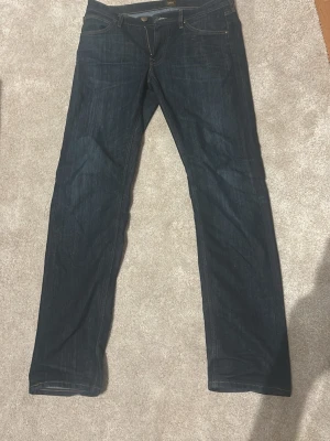 Mörkblå daren zip fly jeans från Lee W32 L32 - Snygga mörkblå jeans från Lee med klassisk femficksdesign och kontrastsömmar. Jeansen har rak passform och är tillverkade i slitstarkt denim-material. Perfekta för dig som vill ha ett stilrent och tidlöst plagg i garderoben.