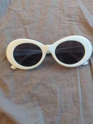Vita ovala solglasögon - Snygga solglasögon med vit, oval båge och mörka glas. Perfekt accessoar för att sticka ut och ge en cool retrovibe till din outfit.