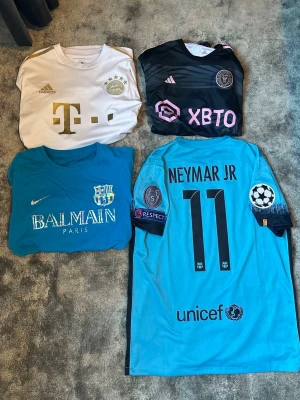 fotbollströjor - Fyra olika fotbollströjor: en vit Bayern München tröja med Adidas med mane 17, en svart Inter Miami med Messi. en blå Barcelona-tröja med Yamal på.  ljusblå Barcelona Neymar skriv om du har några frågor
