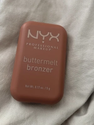 NYX Buttermelt Bronzer Butta Ballin - NYX Buttermelt Bronzer i nyansen Butta Ballin är en krämig bronzer i en kompakt, rektangulär förpackning. Färgen är varm brun och formulan är smörig för enkel applicering. Perfekt för att skapa en solkysst look med naturlig finish. Ny pris 160kr