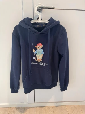Polo Ralph Lauren ”limited edition” hoodie - Mörblå ”limited edition” hoodie från Ralph Lauren med ikoniskt björn tryck på framsidan. Storlek M. Kom vid funderingar!😊
