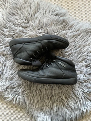 Svarta skinnkängor från Timberland - Säljer ett par svarta kängor från Timberland i skinn med snörning och robust sula. Klassisk modell med diskret logga på sidan och bekväm passform. Perfekta för dig som vill ha stilrena boots till höst och vinter.