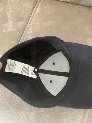 Svart under armour keps - Snygg svart keps med böjd skärm och sex paneler.Jag köpte den för 2 veckor sen men den är för stor 