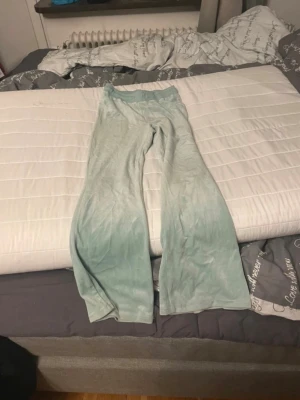 Mintgröna utsvängda leggings - Säljer ett par mintgröna leggings med utsvängda ben och hög midja. De har en mjuk och stretchig känsla, perfekta för en avslappnad och trendig look. Materialet ser ut att vara bomull eller en bomullsblandning. Snygga att styla med en oversized hoodie eller crop top. Snöret saknas bara men funkar lika bra och den är i 152