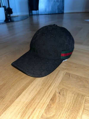 Svart keps från Gucci med logomönster - Svart keps från Gucci med diskret GG-logomönster. Kepsen är använd max 10 gånger. Jag säljer den pga att den är för liten. Självklart äkta