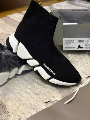 Balenciaga Speed Trainer sneakers svart - Säljer ett par svarta Balenciaga Speed Trainer sneakers med vit chunky sula och stickad ovandel. Skorna har Balenciaga-logga på sidan och en strumpliknande passform som sitter tight runt foten. Perfekta för dig som gillar streetwear och modern design.