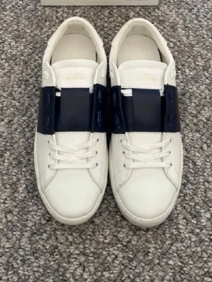 Valentino vita sneakers med blå rem - Feta Valentinos i nyskick med ett billigt pris, perfekta inför den kommande sommaren à Påse samt dustbag ingår, skriv om du har frågor om skorna. Storlek 41 i färgen Marinblå