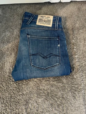 Blå jeans från Replay - Snygga blå jeans från Replay med klassisk femficksdesign och coola slitningar. Jeansen har en rak passform och tydliga kontrastsömmar. Märkespatch bak i midjan och detaljerade bakfickor. Perfekta för en avslappnad stil. Modellen är anbass och dessa jeans är inte använda mycket. Ställ gärna frågor😌