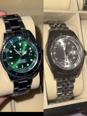 Rollie 2X - Två stilrena herrklockor. Den ena har grön urtavla och vridbar bezel, den andra har silverfärgad urtavla med stenar som index och räfflad bezel. Båda har armband i rostfritt stål och klassisk design. Perfekta accessoarer för dig som gillar exklusiv stil.