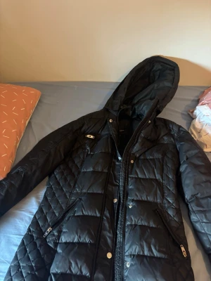 Svart pufferjacka från Rockandblue - Snygg svart vinterjacka med huva och avtagbar päls som ingår. Varm och skön, perfekt för kalla dagar. Stilren design som passar till allt.  Jackan är i bra skick men det finns ett litet hål där bak (syns knappt vid användning). Därför säljs den till ett bra pris.