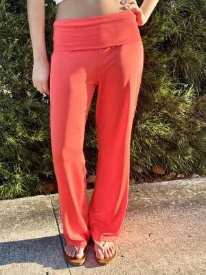 Koralröda mjukisbyxor med bred linning - ALDRIG ANVÄNDA! Säljer ett par av dem väldigt populära korallfärgade mjukisbyxorna med bred, vikbar linning och raka ben. Byxorna har en avslappnad passform och är tillverkade i ett mjukt, stretchigt material som känns skönt mot huden. Perfekta för chill dagar hemma eller när du vill vara bekväm.