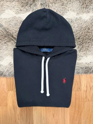 Svart Polo Ralph Lauren Fleece Hoodie - Storlek S - Hej! 👋 Säljer en klassisk svart Polo Ralph Lauren fleece-hoodie i storlek S med snygg röd pony-logga. 🐎 En tidlös favorit som alltid sitter helt rätt! Tröjan är i mycket gott skick och välvårdad. 100% äkta – alla originaltvättlappar finns kvar. QR-koden visar just nu "authentication check", vilket är en säkerhetsspärr som triggas vid upprepad skanning på andrahandsmarknaden. Det är alltså inte ett tecken på att den är falsk, utan bevis på att den varit populär! ✨ Ett riktigt premiumfynd.✅🙌