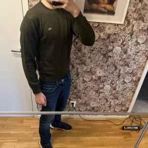  Lacoste stickad tröja - Snygg mörkgrön tröja från Lacoste med den klassiska krokodilloggan på bröstet. Tröjan har rund halsringning och långa ärmar. Storlek 2 som motsvarar xs men den sitter tydligt som en S. Jag bär S-M och den passa mig mycket bra