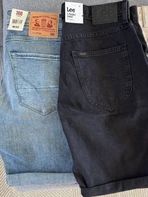 3-pack shorts i denim och bomull - Säljer tre par shorts: ett par ljusblå denimshorts med klassisk femficksdesign, ett par svarta Lee 5 Pocket Shorts i bomull och ett par beige bomullsshorts. Alla har normal passform och raka ben, perfekta för sommaren. Denim & de svarta shortsen säljs för 250kr och de beiga för 300kr. Storlek syns på bilden!