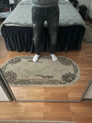 Replay jeans med slitningar  - Säljer ett par svarta replay  jeans med slitningar och hål på knäna och låren. Jeansen har en tight passform och klassisk femficksdesign. Perfekta för en trendig och avslappnad stil. ( extremt sällsynta) W33 och L34. Modellen är 185 och cg väger 78kg