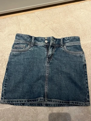 jeanskjol - Superfin mini-jeanskjol med snygga fickor och extra brett midjeband med 2 knappar. Den sitter ganska tajt men tyget är också ganska stretchig! 