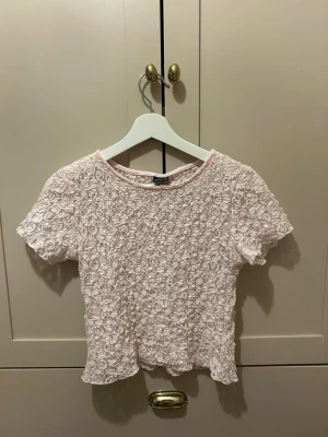 ljusrosa spetsblus från Gina Tricot - söt ljusrosa blus från Gina Tricot med korta ärmar och rund hals. Toppen är helt täckt av spets med blommigt mönster