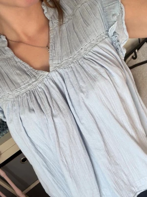 Ljusblå volangblus🫶🏻 - Supersöt ljusblå blus med volangärmar och spetsdetaljer. Blusen har v-ringning, rynkade partier och är tillverkad i ett tunt, luftigt tyg som ger en avslappnad känsla. Perfekt för en fräsch och somrig look. Jätte söt!🤍