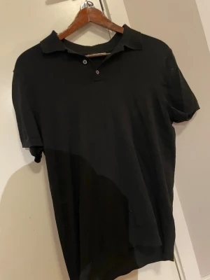 Zara pikétröja  - Klassisk svart pikétröja med kort ärm och krage. Tröjan har två knappar vid halsen och är tillverkad i ett mjukt material som passar perfekt till både jeans och shorts. Tröjan är nästintill oanvänd. 