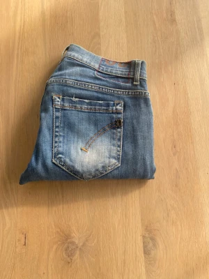Dondup jeans  - Snygga Blåa jeans från Dondup med klassisk femficksdesign och en slim passform. Jeansen har en diskret tvättad look med slitningar och är tillverkade i stretchigt denim för en bekväm passform. Perfekta för en stilren och modern look.