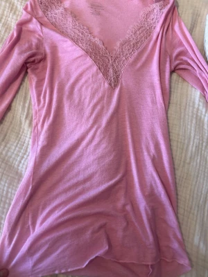 Rosa topp  med spets från Intimissimi - Supersött rosa nattlinne från Intimissimi med djup V-ringning och spetsdetaljer vid halsen. Tillverkat i en mjuk blandning med kashmir som känns lyxig mot huden. Perfekt för mysiga kvällar hemma. Använd typ en gång.