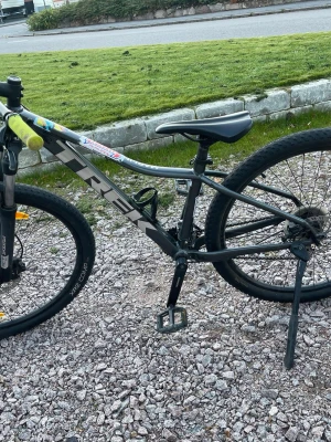 Svart cykel med neonhandtag - Säljer en svart cykel från Trek med neonfärgade handtag och robust ram. Cykeln har grova däck och är utrustad med framgaffel för terräng. Perfekt för dig som vill ha en cool och sportig cykel.