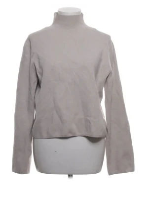 Beige stickad tröja med hög krage - En stilren beige stickad tröja med hög krage och långa ärmar. Tröjan har en enkel design utan mönster och är tillverkad i ett mjukt material som passar perfekt för lager-på-lager. Perfekt för dig som gillar minimalistisk stil.