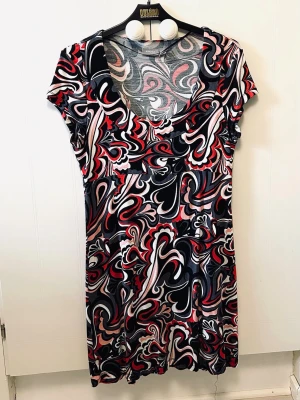 Mönstrad kortklänning med v-ringning - Kortklänning med färgstarkt abstrakt mönster i svart, vit, röd och rosa. Klänningen har u-ringning och korta ärmar, tillverkad i ett mjukt och stretchigt material. Perfekt för dig som gillar statement-plagg och vill sticka ut. Ny, endast tagg borttagen.