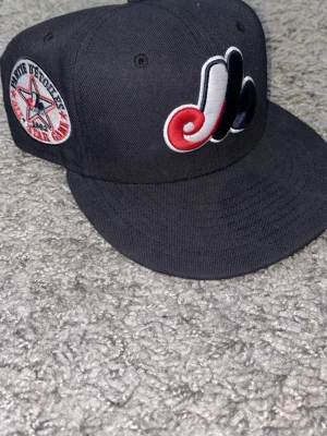 Mörkblå new era keps montreal expos - Snygg mörkblå keps från New Era med Montreal Expos logga broderad framtill i rött, vitt och blått. På sidan finns en patch med text och stjärna samt New Era-loggan broderad i rött. Den är väldigt fint skick då den är lite liten på mig, storlek 7 1/4 . Och  57.7 cm