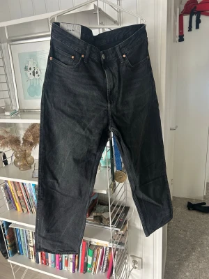 Svarta loose fit jeans från H&M - Säljer ett par svarta loose fit jeans från H&M. Jeansen har klassisk femficksdesign, raka ben och är tillverkade i kraftigt denimtyg. Perfekta för en avslappnad och trendig stil. Passar dig som gillar bredare passform och streetwear-vibe.