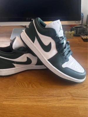 Air Jordan 1 Low vit/grön - Snygga Air Jordan 1 Low sneakers i vitt och mörkgrönt läder. Knappt använda