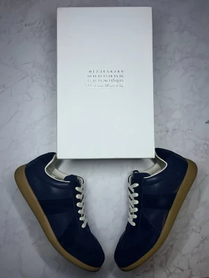 Marinblå Maison Margiela gats - Snygga marinblå sneakers från Maison Margiela. ALDRIG ANVÄNT🤩 Boxen och skorna följs med vid köp🤝 går jättegärna ner vid pris vid snabbaffärer, skriv gärna nåt ifall du funderar över nåt🙌🏻