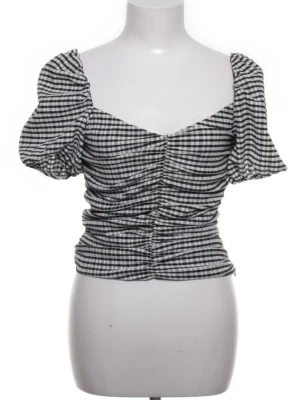 Rutig svartvit blus med puffärm - Trendig rutig blus i svart och vitt med puffiga korta ärmar och rynkade detaljer framtill. Snygg v-ringning och figurnära passform som ger en modern siluett. Perfekt för dig som vill sticka ut med en klassisk men cool topp.
