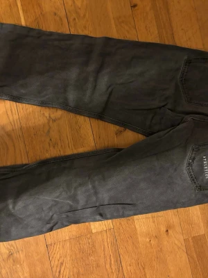 Gråa jeans från District 46 - Snygga grå jeans från District 46 med klassisk femficksmodell och raka ben. Jeansen har diskreta sömmar och är tillverkade i ett mjukt bomullsmaterial med lite stretch för extra komfort. Perfekta till en avslappnad stil.