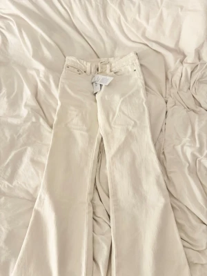 Vita lågmidjade bootcut jeans  - Säljer ett par lågmidjade vita bootcut jeans från gina tricot. aldrig använda med lappen kvar. slutsålda!😊storlek 32 men passar även en 34