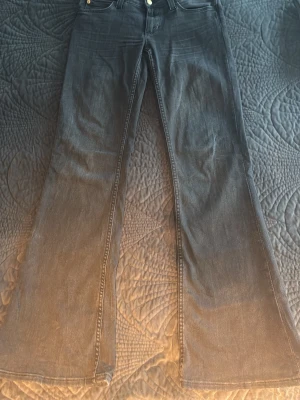 Svarta utsvängda jeans Cheap Monday - Säljer ett par svarta jeans från Cheap Monday med utsvängda ben och klassisk femficksdesign. Jeansen har en cool logga med döskalle på bakfickan och är tillverkade i denim. Perfekta för dig som gillar retrostil och vill sticka ut.