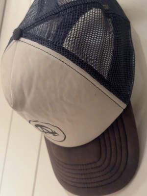 All cap one keps - Säljer en stilren all cap one keps med blå frontpanel och mörkblått nät baktill. Skärmen är också mörkblå och kepsen har en svart logotyp framtill. Justerbar baktill för perfekt passform. Perfekt för dig som gillar en avslappnad streetstil.