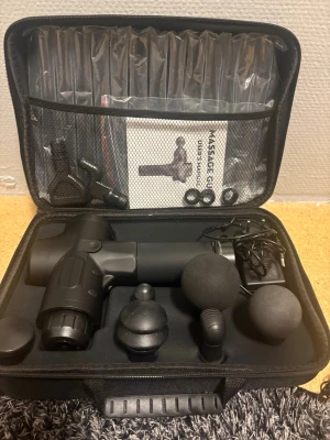 Massagepistol med tillbehör i väska - Säljer en svart massagepistol i hård väska med flera utbytbara massagehuvuden och laddare. Perfekt för återhämtning efter träning eller för att mjuka upp stela muskler. Allt ligger organiserat i en praktisk förvaringsväska.