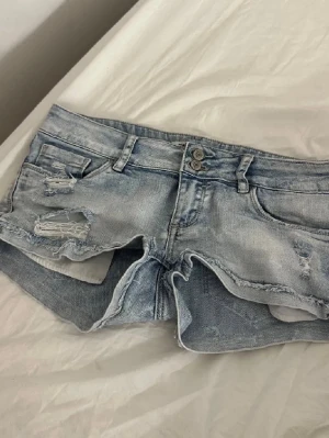 Ljusa slitna jeansshorts med rå kant - Säljer ett par ljusblå jeansshorts med slitningar och råa kanter. Midjemåttet är 38 cm tvärs över!❤️