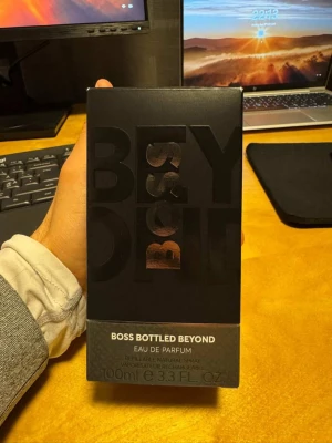 Boss Bottled Beyond Eau de Parfum - Boss Bottled Beyond Eau de Parfum från Hugo Boss i en snygg svart glasflaska med silverdetaljer och tydlig BOSS-logga. Flaskan rymmer 100 ml och har en modern, stilren design som känns lyxig och maskulin. Parfymen är nästan helt ny – jag har bara sprayat 2–3 gånger för att testa doften. Nypris är 1500 kr. 