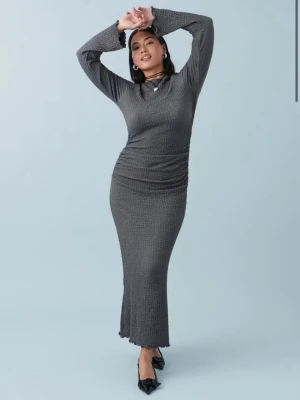 Textured maxi dress - Ginatricot - Säljer en snygg grå långklänning med ribbad struktur och långärmade ärmar. Klänningen har en figurnära passform och är tillverkad i ett mjukt syntetmaterial. Perfekt för dig som gillar stilrena och moderna plagg.